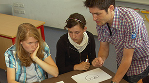 Älterer Schüler unterstützt zwei jüngere Mädchen